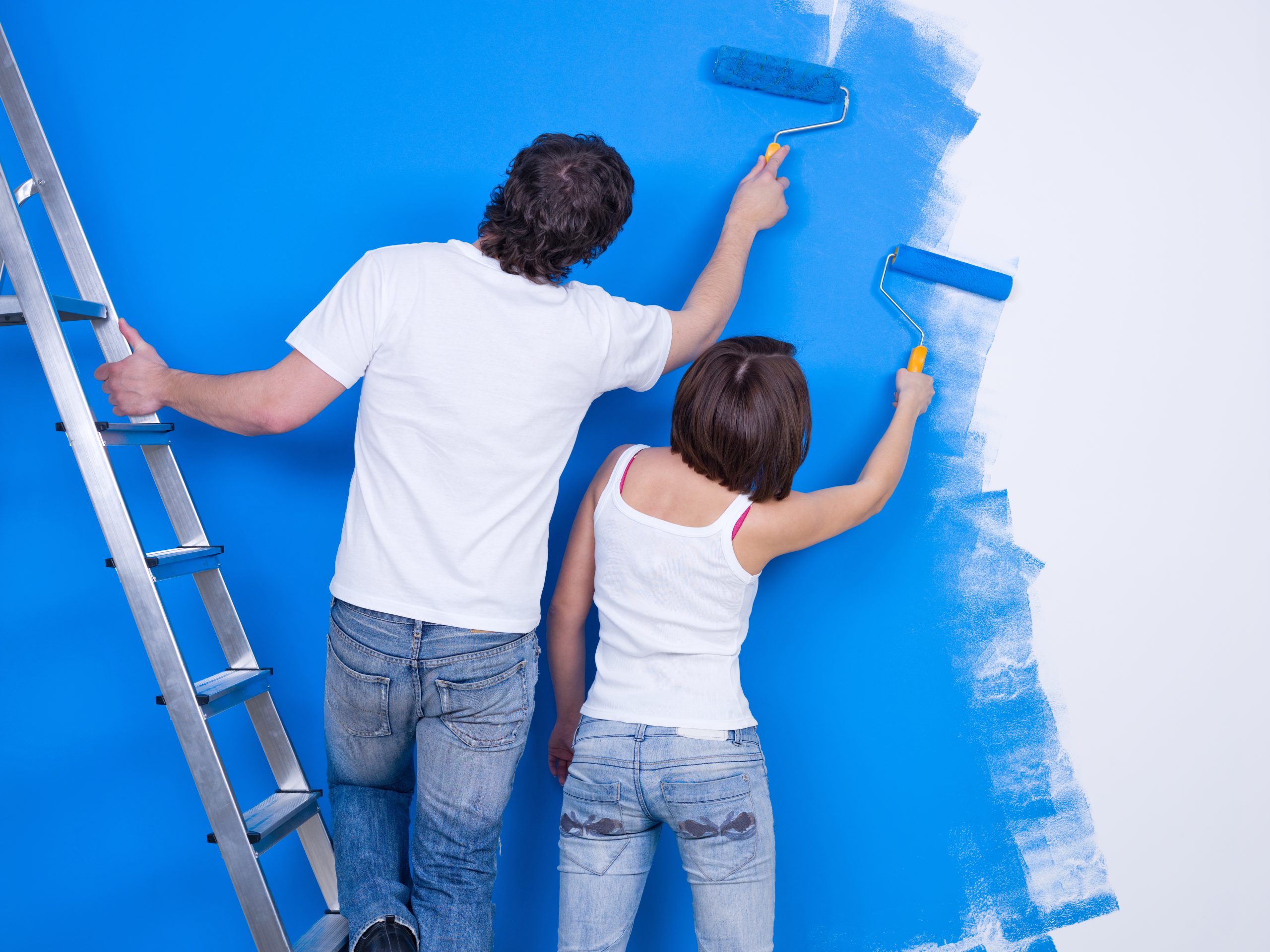 Young couple painting the wall with roller together